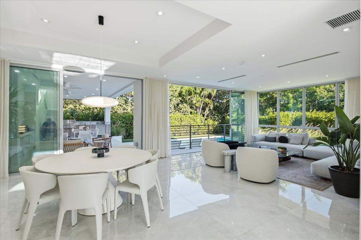 Great room with sliding glass walls fully open to the covered terrace and pool