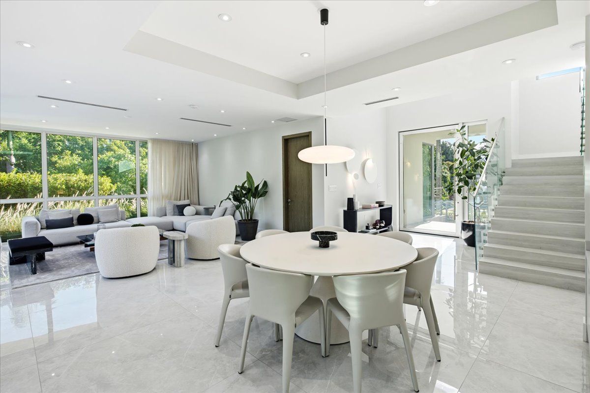 Dining area beside the staircase with its frameless glass railing