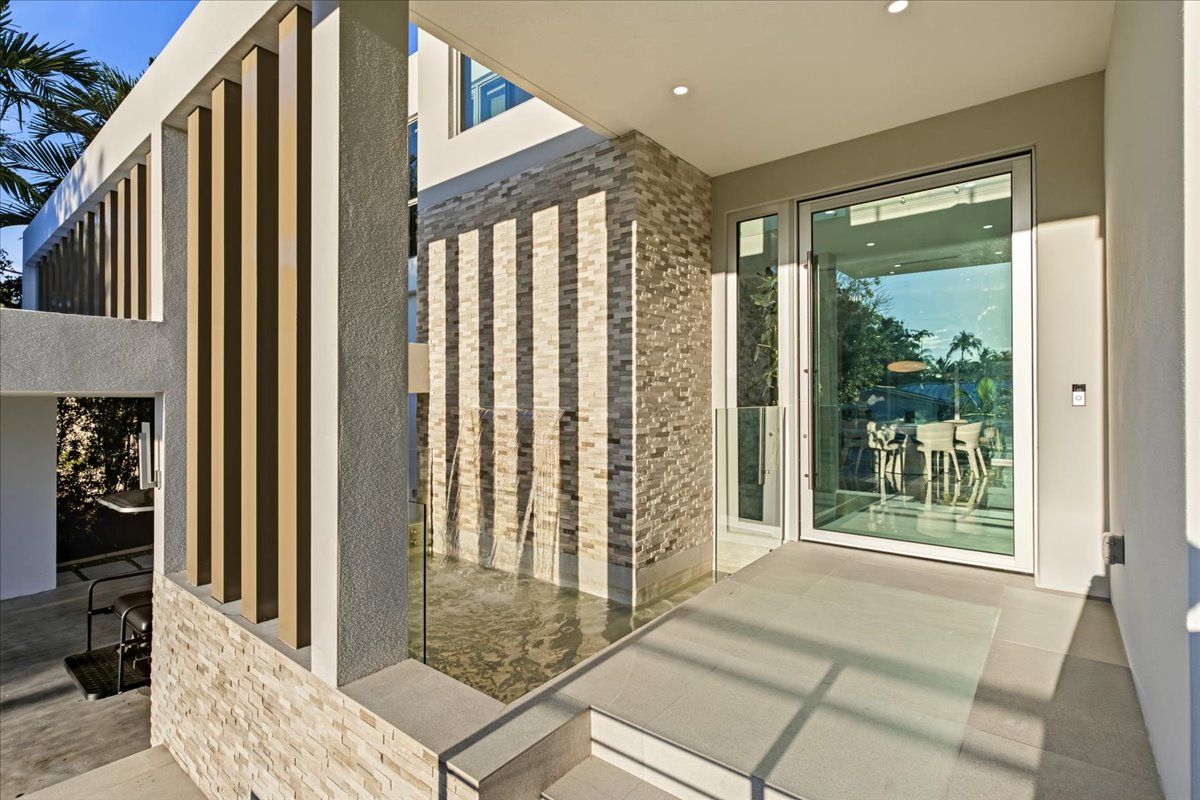 Entry with a waterfall feature against stacked stone beside a full-height glass pivot door