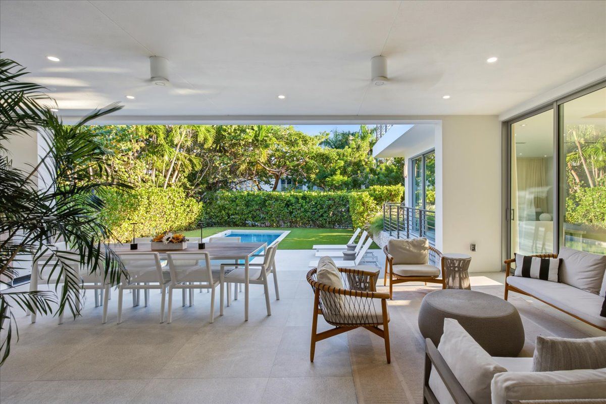 Covered loggia with lounge seating and dining looking out to the pool and garden