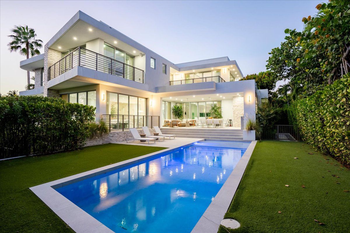 Rear of the home at twilight with the illuminated pool and terrace